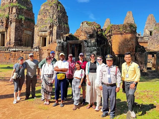 Groep toeristen en een gids poseren voor de tempelruïnes van Preah Khan.