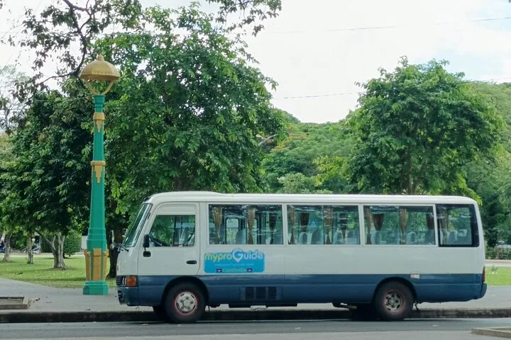 A white and blue tour bus parked next to a green street lamp.