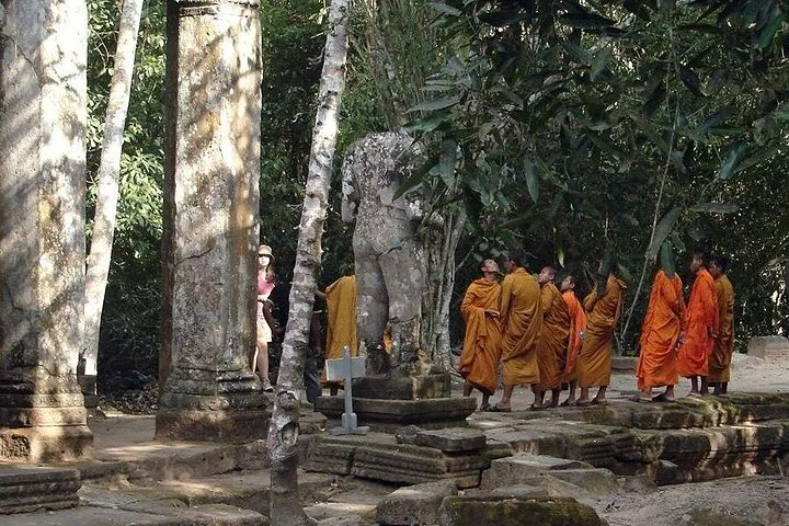 Groep monniken in oranje gewaden tussen de ruïnes van Preah Khan.